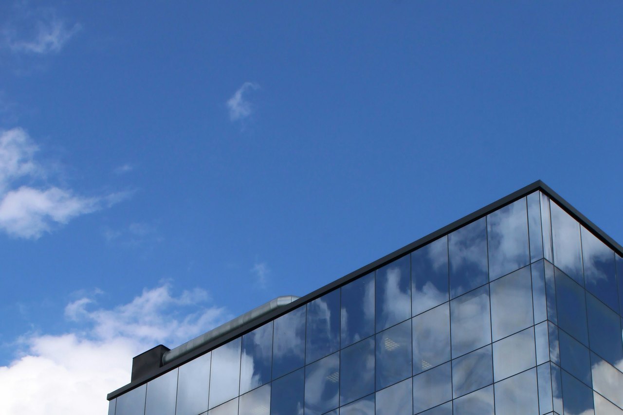 Modern glass hospital architecture beneath an open blue sky