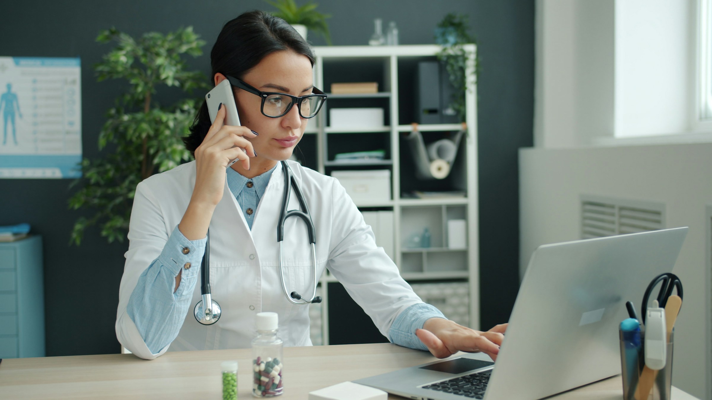 Healthcare professional coordinating work by phone and laptop