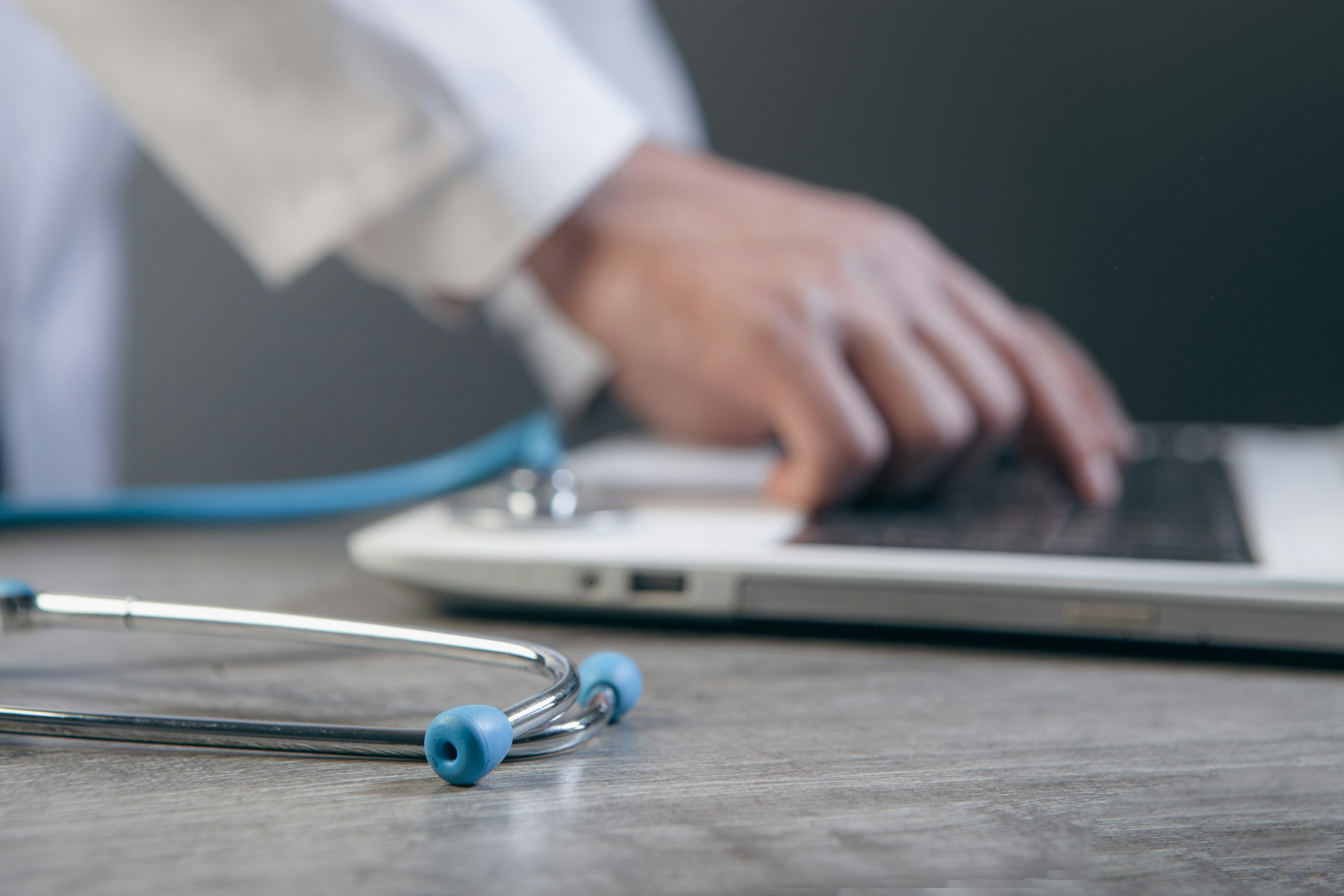 Clinician working with a laptop and stethoscope